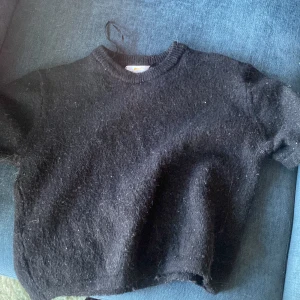 Svart stickad tröja från Gina Tricot - Mysig svart stickad tröja från Gina Tricot. Tröjan har rund halsringning och är kortärmad med en något croppad passform. Perfekt för kyligare dagar och enkel att matcha med olika outfits. Pris kan diskuteras!💕