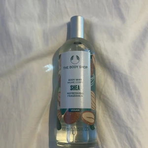 Shea Body Mist från The Body Shop - Fräsch och uppfriskande body mist med sheadoft från The Body Shop. Flaskan är genomskinlig med ett färgglatt mönster av nötter och har en silverfärgad spraykork. Perfekt för en snabb uppfräschning under dagen. Vegansk och kommer i en 100 ml flaska.