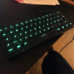 Deltaco Gaming mekaniskt tangentbord - Säljer ett mekaniskt tangentbord från Deltaco Gaming med RGB-belysning. Tangentbordet har en kompakt design och ansluts via USB-kabel. Tangenterna lyser i olika färger, bland annat blått och grönt. Perfekt för gaming eller skrivbordsarbete.