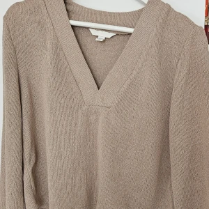 Beige stickad v-ringad tröja - Säljer en beige stickad tröja med v-ringning. Tröjan har lång ärm och är perfekt för lager-på-lager. Enkel och stilren design som passar till det mesta.