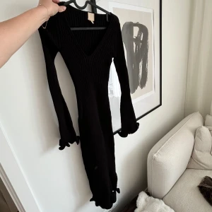 Svart ribbad långklänning från H&M - Väldigt stretchig, har volanger längst med och vid ärmarna. Aldrig använd men inga lappar på