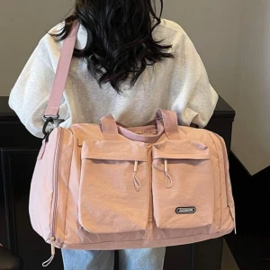Ljusrosa weekendbag med axelrem - Stor och rymlig ljusrosa weekendbag med två stora fickor framtill och fack till skor, även justerbar axelrem. Väskan har även handtag och dragkedja upptill, perfekt för att få med allt du behöver på resan.
