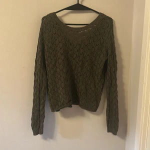 Olivgrön stickad tröja från BikBok - Säljer en olivgrön stickad tröja från BikBok med fint hålmönster. Tröjan har rund halsringning och långa ärmar. Perfekt för lager-på-lager och passar till både jeans och kjol.