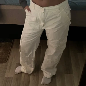 Vita cargopants från Batistini - Säljer ett par vita cargopants från Batistini med normal passform. Byxorna har flera fickor och raka ben, perfekta för en avslappnad stil. Tillverkade i bomull för en skön känsla hela dagen.