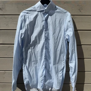 Ljusblå mönstrad skjorta från Stenströms - Säljer en ljusblå skjorta från Stenströms med diskret mönster och klassisk krage. Skjortan har långa ärmar och knäppning framtill. Modellen är Fitted Body vilket ger en smalare passform. Perfekt för dig som gillar stilrena detaljer.