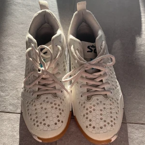 Salming inneskor - Säljer ett par vita Salming sneakers med coolt hexagonmönster och gummisula. Skorna har snörning och är perfekta för träning eller vardag. Lätta och ventilerande med sportig look.