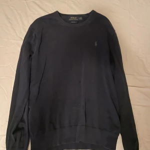 Marinblå från Polo Ralph Lauren - Klassisk svart långärmad tröja från Polo Ralph Lauren i mjuk pima bomull. Enkel design med rund halsringning och diskret broderad logga på bröstet. Perfekt för en stilren och avslappnad look.