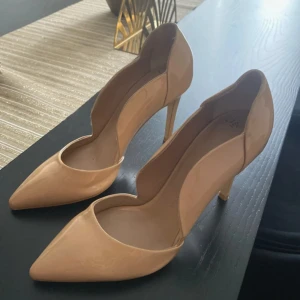 Beige pumps med spetsig tå från Vicenza - Säljer ett par stilrena beige pumps från Vicenza med spetsig tå och hög klack. Skorna har en elegant form och är tillverkade i syntetmaterial med glansig finish. Perfekta för dig som vill ha en klassisk och trendig look.