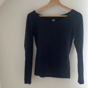 Svart långärmad topp från 157 - En svart långärmad topp från 157 i storlek S. Tillverkad i mjuk bomull med lite stretch för en skön passform. Enkel och stilren design med rund halsringning, perfekt att matcha med jeans eller kjol.