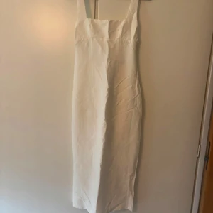 Vit långklänning från Zara - Snygg vit långklänning från Zara med raka breda axelband och stilren design. Klänningen har en enkel, elegant passform och är tillverkad i ett lätt material som passar perfekt till varma dagar. Perfekt för dig som gillar minimalistisk stil.