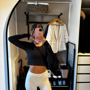 Svart croppad långärmad tröja - Säljer en svart croppad långärmad tröja med rund halsringning. Tröjan är ribbad och har en tight passform som framhäver midjan. Perfekt att styla med höga byxor eller kjol för en trendig look.