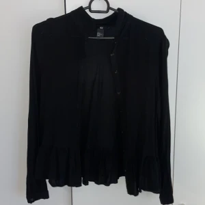 supersöt svart volangkofta - säljer denna svarta volangkoftan med låg krage som passar till det mesta!! perfekt nu till hösten! skriv för ytligare funderingar ❣️använd endast en gång men har inga tecken på användning
