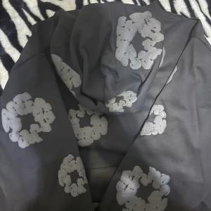 Svarta mjukisbyxor med blommigt tryck - Svarta mjukisbyxor med elastisk midja och snörning. Byxorna har stora, gråblommiga tryck i cirkelform över hela tyget som ger en cool och unik vibe. Perfekta för chill dagar eller när du vill ha något bekvämt men ändå sticker ut.