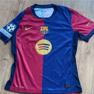 FC Barcelona Lamine Yamal matchtröja - Barça matchtröja med Lamine Yamal 19-tryck, klassisk halva-röd halva-blå design, guldiga detaljer och klubbmärke. Nike Dri-FIT ADV-material, Champions League-märke på ärmen och Spotify-logga på bröstet. Perfekt för dig som älskar fotboll och vill sticka ut.