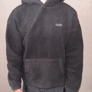 Svart fleece hoodie från Levi's - Mysig svart hoodie från Levi's i fleece med stor huva och magficka framtill. Perfekt för kyliga dagar, med relaxed fit och diskret Levi's-logga på bröstet. Riktigt skön att dra på sig när du vill vara både varm och stilren. Aldrig använd. Köpt på Zalando för 460:- Storlek S men passar M bättre!