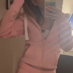Rosa hoodie med dragkedja RUSSEMERCH  - Säljer en ljusrosa hoodie med dragkedja och huva. Tröjan har långa ärmar, vita snören i huvan och en skön, avslappnad passform. Perfekt för chill dagar eller när du vill vara extra comfy.