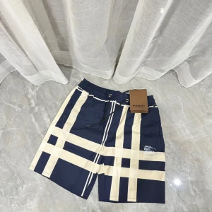 Blå-rutiga Burberry shorts med snörning - Snygga shorts från Burberry i marinblått och beige med klassiskt rutigt mönster. De har elastisk midja med svart snörning och Burberry-logga framtill. Perfekta för sommaren och riktigt stilrena till streetwear eller chill dagar.
