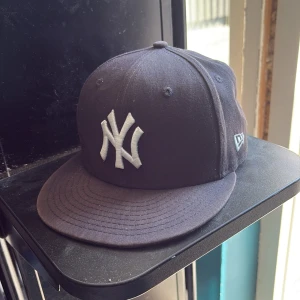 Svart New Era Yankees keps 9FIFTY - Säljer en svart New Era 9FIFTY snapback-keps men den är lite solblekt vid snabb affär priset kan diskuteras med klassiskt New York Yankees-broderi i vitt framtill. Kepsen har rak skärm, justerbar snapback baktill och är tillverkad i bomull. Perfekt för dig som gillar sportig streetstyle. 