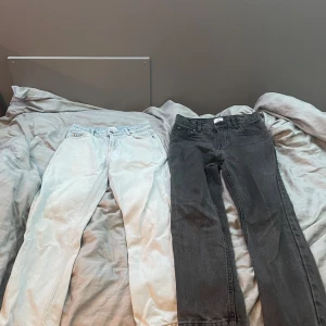 Två par jeans från Grunt ljusblåa & svarta - Säljer två par jeans: ett par ljusblå raka jeans från Grunt med klassisk femficksdesign och ett par svarta jeans med rak passform. Båda har normal midja och är tillverkade i bomullsdenim. Perfekta för en chill och stilren look.storleken på båda jeansen är 23!!