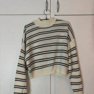 Randig stickad tröja från H&M  - Superfin stickad tröja från H&M Divided i vitt med svarta ränder. Tröjan har en ribbad, hög hals och långa ärmar. Den är lite croppad. Storlek S, aldrig använd men ingen prislapp är kvar.