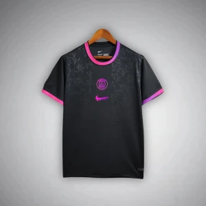 Svart PSG x Nike fotbollströja - Svart PSG fotbollströja från Nike med subtilt blommönster i tyget. Tröjan har korta ärmar med lila och rosa detaljer vid ärmslut och krage. PSG-logga och Nike Swoosh i neonrosa framtill. Tillverkad i lätt och ventilerande polyester.