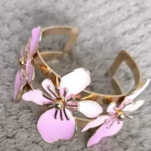 Järn armband med rosa blommor - Unikt armband i järn med stora, ljusrosa blommor i metall och emalj. Blommorna har fina detaljer och ger ett riktigt statement till din look. Perfekt för dig som vill sticka ut med ett färgglatt och trendigt smycke.
