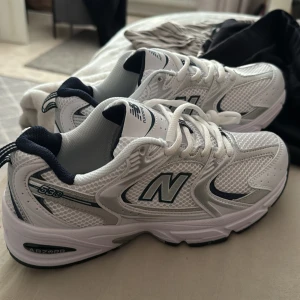 New Balance 530 vita sneakers - Säljer dessa då de inte passar mig.        Storlek 39,passar även 38……Snygga New Balance 530 sneakers i vitt med silvriga och mörkblå detaljer. Ovandelen är i mesh och syntet för en sportig vibe, med klassisk snörning och rund tå. Perfekta för dig som gillar retrostil och bekväma skor till vardags.  Säljer dessa då de inte passar mig