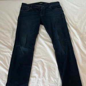 Mörkblå jeans från Jack & Jones (Slim/Glenn) - Snygga mörkblå jeans från Jack & Jones med klassisk femficksdesign. De har en normal passform och är tillverkade i bomull för en bekväm känsla. Perfekta för en avslappnad stil. Nypris: 799:-