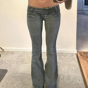 Grå bootcut jeans - Snygga grå bootcut jeans med låg midja och klassisk femficksdesign. Mättet är 37 rakt över och 77 innerben och grenen 17 cm hög. Dessa bilder är av de jag köpte de av och de sitter samma på mig om jag har klackar (i längden). Jag är ca 160 så de passar mellan 160-170!