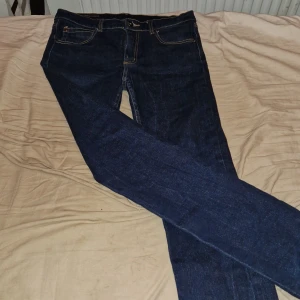Mörkblå jeans från Fuzzy - Snygga mörkblå jeans från Fuzzy i storlek 32. Tillverkade av 98% bomull och 2% spandex för en bekväm passform. Klassisk design med fem fickor och knappgylf. Perfekt för en stilren look.