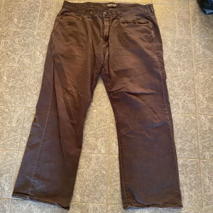 Bruna byxor från Kirkland Signature - Säljer ett par bruna byxor från Kirkland Signature köpta i usa. Byxorna har en rak passform med slitage.