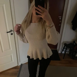Stickad tröja - Säljer en beige ribbad tröja från ONLY med volangdetalj i nederkant. Tröjan har långa ärmar och en rund halsringning💕
