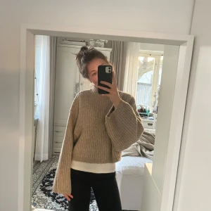 Beige stickad tröja - Säljer en mysig beige stickad tröja med en lös passform. Tröjan har långa ärmar och en ribbad struktur. Tyvärr har den ett litet hål men som går att lösa med virknål