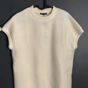 Vit ärmlös topp från Zara - Säljer en stilren vit ärmlös topp från Zara. Perfekt för lager-på-lager eller som den är. Toppen har en rund halsringning och är tillverkad i ett mjukt material.