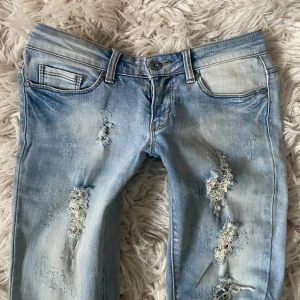 Ljusblåa super lågmidjade bootcut jeans med slitningar  - SÄLJER ÄCEN ETT PAR ANDRA LIKNANDE FAST MÖRKARE💞Världens snyggaste och finaste och sååå sjukt lågmidjade ljusblåa bootcut jeans med hål, utsydda själv till bootcut (skriv till mig för mer info/bilder på hur ja sytt)💞 Midjemått: ca 36 cm +stretch💞 Innerbenslängd: ca 83-84 cm💞 Grenhöjd: ca 15,5 cm💞