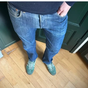 Levi’s 501 - Säljer ett par klassiska blå jeans från Levi's. De har en straight passform och är tillverkade i slitstarkt denim. Byxorna har fem fickor och en knappgylf. Perfekta för en avslappnad stil.