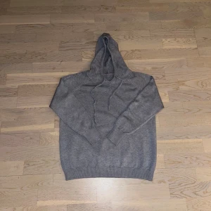 Merinoull hoodie - Säljer en stilren grå merinoull hoodie med långa ärmar och justerbar huva. Perfekt för en avslappnad look. Ribbstickade muddar vid ärmslut och nederkant ger en skön passform. Den passar om du har mellan xs och xxs 