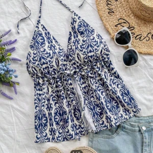 Blåvit mönstrad linnetopp - Säljer en snygg blåvit linnetopp med ett iögonfallande mönster. Toppen har smala axelband och en knytning framtill som ger en fin detalj. Perfekt för varma sommardagar!