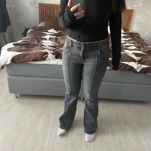 Grå bootcut jeans - Snygga grå bootcut jeans med en klassisk look. De är low/mid. Jeansen har en dragkedja och knappar framtill samt fickor både fram och bak. Passar även som L och är stretchig i materialet. Har även tänder framtill. Inga defekter 