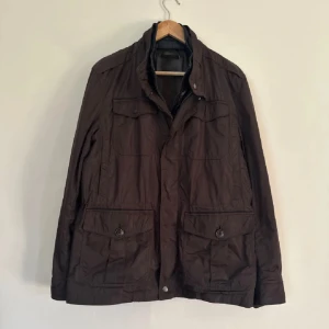 Massimo dutti Field Jacket - Säljer en stilren brun jacka från Massimo dutti med dragkedja och knappar. Jackan har flera praktiska fickor och en hög krage för extra skydd. Perfekt för höst och vår och sommarkvällar. Skick 9/10. Skriv för frågor