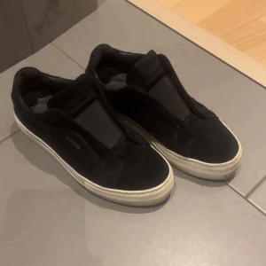 Axel arigato - Snygga svarta skor från arigatos.. Skorna har en vit sula och är perfekta för en avslappnad look. De är utan snörning vilket ger en smidig och modern känsla. Knappt använda. Tror tyvärr inte jag har boxen kvar,men påsen får man med. Pris kan diskuteras 
