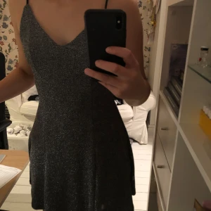 Glittrig klänning - Säljer en glittrig klänning från hm med en låg rygg och banden gör ett kors, klänningen sitter väldigt snyggt då den är lite figursydd 🤩