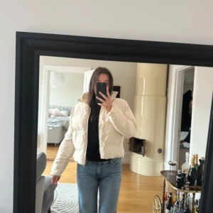 Gräddvit pufferjacka - Jackan har en dragkedja framtill och är perfekt för kyligare dagar. Den har en croppad passform som ger en modern look. Perfekt för att hålla sig varm och stilren. Lite smutsig men lätt att tvätta! Står ingen stl men passar S/M