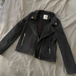 Svart mockajacka från Lindex - svart lite tunnare kort mocka jacka från lindex i stl 152 men passar mig som har xs💞 jätte fint skick!