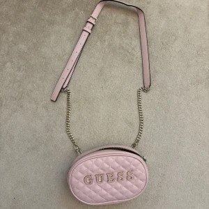 INTRESSEKOLL på väska från guess - Så himla fin rosa classy väska från guess. Aldrig använd. Du kan ta bort bandet och använda själva väskan som necessär också ifall man vill det! 
