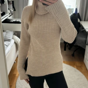 Beige ribbstickad tröja - Beige ribbstickad tröja med sluts på båda sidorna. Normal i storleken och endast använd 1 gång!