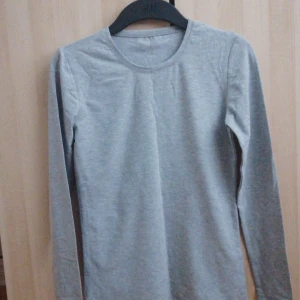 Grå långärmad tröja - Säljer en enkel och stilren grå långärmad tröja i bomull och lycra. Perfekt för en avslappnad look. Tröjan har en rund halsringning och är tillverkad i Turkiet.