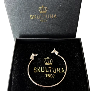 Skultuna CTG Horse Cuff Thin Silverplätterar  armband från Skultuna - Elegant silverfärgat armband från Skultuna med hästhuvuden som detaljer. Perfekt för den som älskar stilrena accessoarer med en unik touch. Kommer i originalförpackning.