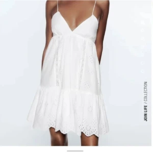 Vit klänning med spetsdetaljer - Söt vit klänning med tunna axelband och v-ringning. Klänningen har spetsdetaljer och en volangkant nedtill. Den har en öppen rygg med knytning för en justerbar passform, perfekt för student eller midsommar💛stl M men passar S också 