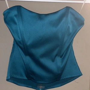 Blå axelbandslös topp korsett - Snygg blå axelbandslös topp i satin med dragkedja bak. Korsett Perfekt för en stilren look.